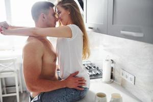 Young couple embracing and kissing each other on the kitchen photo