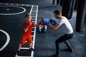 el joven entrenador enseña a los niños el deporte del boxeo en el gimnasio foto