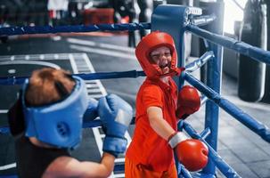 Two boys in protective equipment have sparring and fighting on the boxing ring photo