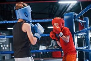 Two boys in protective equipment have sparring and fighting on the boxing ring photo