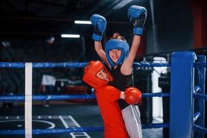 Portrait of two young boys in protective gloves celebrating victory on boxing ring photo