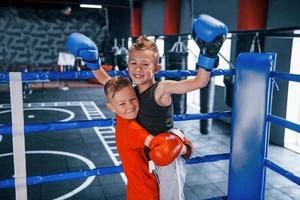 Portrait of two young boys in protective gloves celebrating victory on boxing ring photo