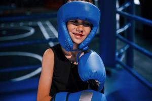 Little boy in protective wear and with nose bleed training in the boxing ring photo