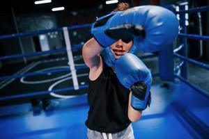 Little boy in protective wear and with nose bleed training in the boxing ring photo