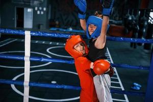 Portrait of two young boys in protective gloves celebrating victory on boxing ring photo