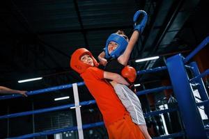 Portrait of two young boys in protective gloves celebrating victory on boxing ring photo