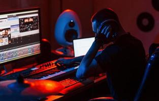 joven ingeniero de sonido trabajando y mezclando música en interiores en el estudio foto