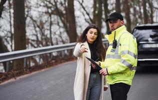 oficial de policía masculino con uniforme verde hablando con la dueña del camión en la carretera foto