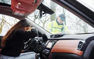 Girls feels bad. Male police officer in green uniform checking vehicle on the road photo