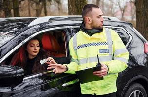 Male police officer in green uniform takes bribe from woman in car photo