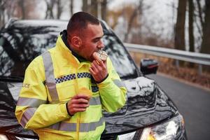 Male police officer in green uniform taking a break with donut on the road photo