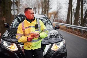 Male police officer in green uniform taking a break with donut on the road photo