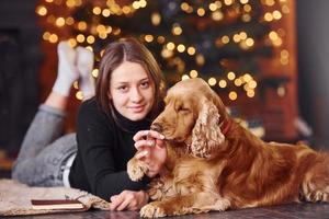Young girl lying down in christmas decorated room with her dog photo