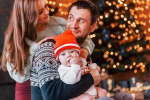 Father and mother with their child together in christmas decorated room photo