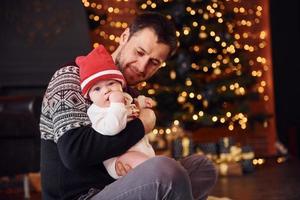 padre con su hijo juntos en una habitación decorada con navidad foto