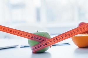 Apple and orange lying down on the table with measuring length on it photo