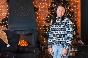 Happy woman in christmas clothes standing in the New year decorated room photo