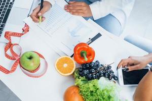 Top view of female nutritionist that gives consultation to patient indoors in the office photo