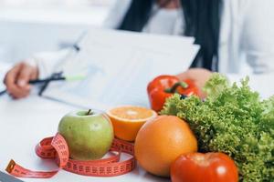 Female nutritionist in white coat sitting indoors in the office at workplace photo