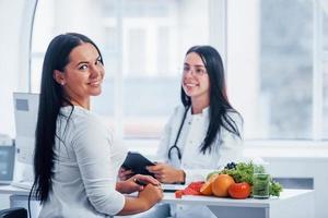 Female nutritionist gives consultation to patient indoors in the office photo