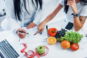 vista superior de la nutricionista femenina que da consulta al paciente en el interior de la oficina foto