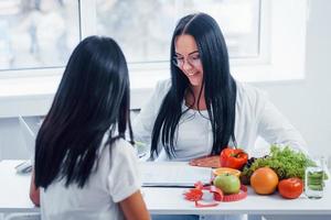 Female nutritionist gives consultation to patient indoors in the office photo