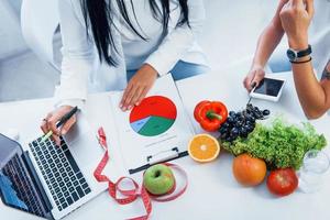 Top view of female nutritionist that gives consultation to patient indoors in the office photo