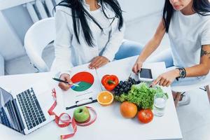 vista superior de la nutricionista femenina que da consulta al paciente en el interior de la oficina foto