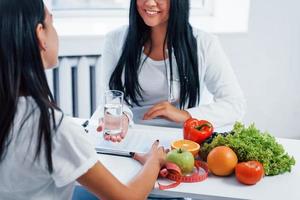 Female nutritionist gives consultation to patient indoors in the office photo