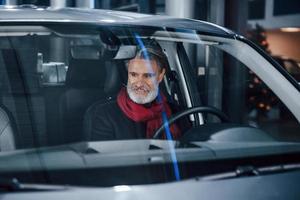 un anciano moderno y elegante con pelo gris y bigote está en el coche moderno foto