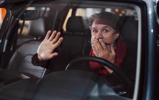 un anciano alegre y elegante con el pelo gris se divierte en el coche moderno foto