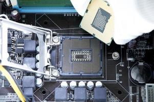Top view of motherboard and technician about to insert CPU chip. photo