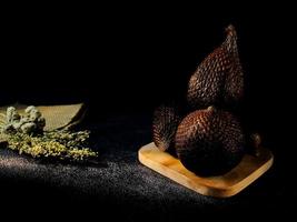Salak is a type of palm fruit commonly eaten. snake fruit, its scientific name is Salacca zalacca. black sand background. photo