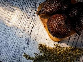 Salak is a type of palm fruit commonly eaten. snake fruit, its scientific name is Salacca zalacca. white wood background. photo