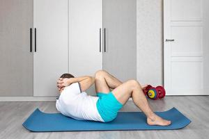 un hombre fuerte, saludable y con músculos, entrenando en casa. ejercicios para los musculos de la prensa foto