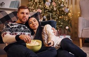 Una pareja joven abrazándose unos a otros en el interior de una habitación decorada con Navidad foto