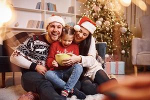 Happy family indoors in christmas hats have fun together and celebrating new year photo