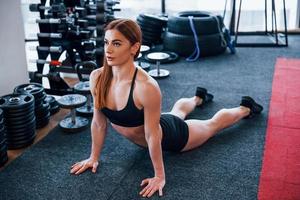 joven deportista vestida de negro haciendo ejercicios de estiramiento en el gimnasio foto