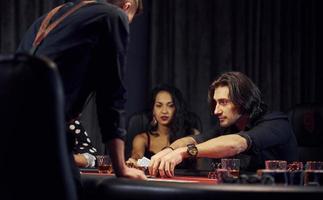 Group of elegant young people that playing poker in casino together photo