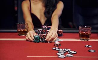 Woman in elegant clothes sits in cassino by table and plays poker game photo