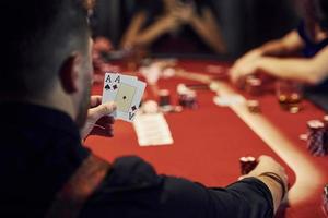 Guy have pair of aces. Group of elegant young people that playing poker in casino together photo