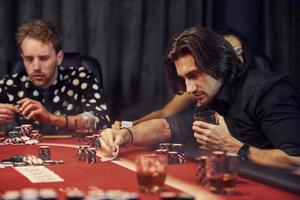 With glasses of drink. Group of elegant young people that playing poker in casino together photo