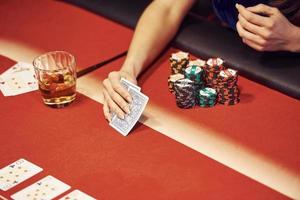 vista de cerca de las manos de la mujer. chica juega al póquer en la mesa del casino foto