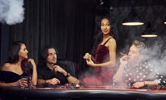 Group of elegant young people that playing poker in casino together photo