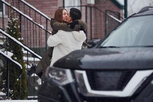 una pareja joven da un paseo al aire libre cerca del coche en invierno foto