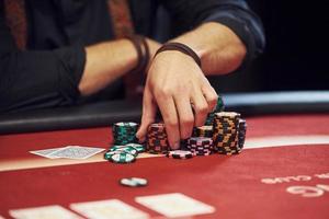 Close up view of man's hands. Guy plays poker game by table in casino photo