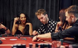 Group of elegant young people that playing poker in casino together photo