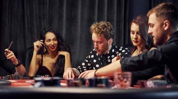 grupo de jóvenes elegantes que juegan al póquer en el casino juntos foto