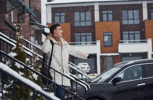 Man with christmas tree standing on the ladder of building near car photo