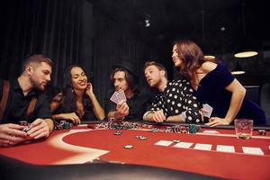 grupo de jóvenes elegantes que juegan al póquer en el casino juntos foto